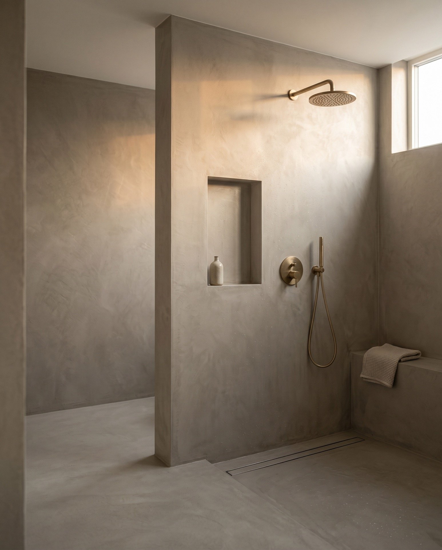 A walk in shower with seamless microcement walls and floor